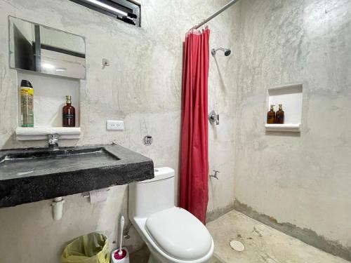 a bathroom with a toilet and a red shower curtain at Casa y departamentos lavanda in Mérida