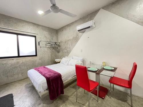 a bedroom with a bed and a table with red chairs at Casa y departamentos lavanda in Mérida