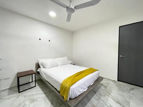 a bedroom with a bed with a yellow blanket on it at Casa y departamentos lavanda in Mérida