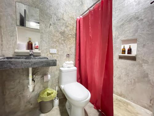 a bathroom with a toilet and a red shower curtain at Casa y departamentos lavanda in Mérida