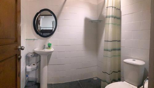 ein Badezimmer mit einem Waschbecken, einem WC und einem Spiegel in der Unterkunft Tamarindo Backpackers in Tamarindo