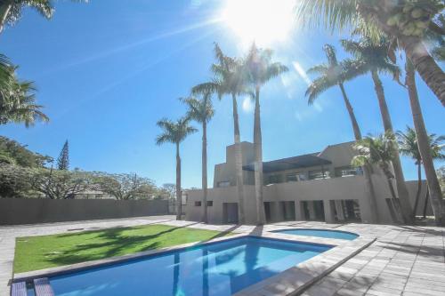 une maison avec des palmiers et une piscine dans l'établissement Gales Park Hotel, à Dourados