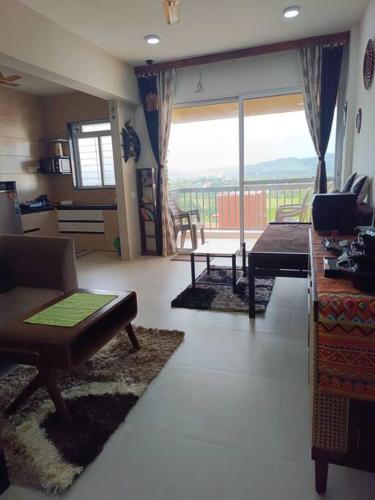 a living room filled with furniture and a large window at Cozy Home near Bhavali Dam in Igatpuri