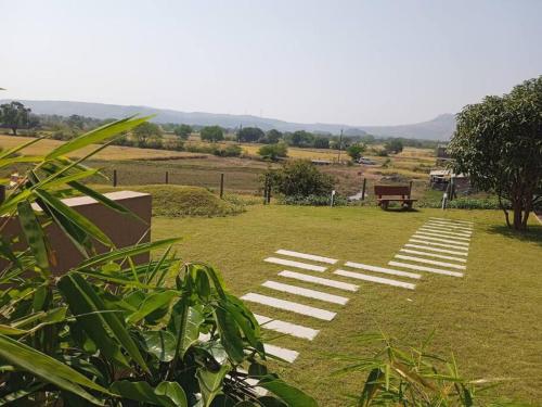 a pathway in the grass with a bench in a field at Cozy Home near Bhavali Dam in Igatpuri