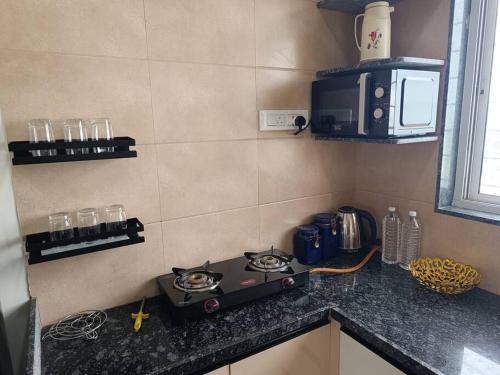 a kitchen counter with a stove and a microwave at Cozy Home near Bhavali Dam in Igatpuri