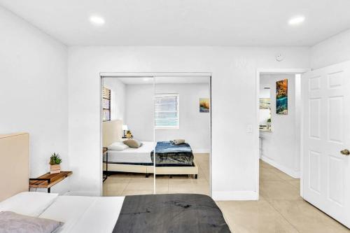 Habitación blanca con cama y espejo en New Stylish 2 Bdrm Mins To Beach & Aventura Mall en Hallandale Beach