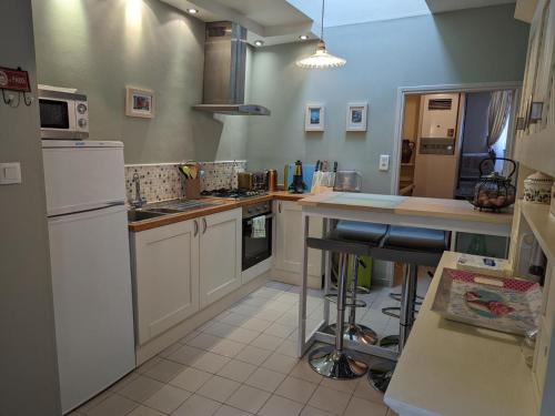 une cuisine avec des armoires blanches et un comptoir dans l'établissement Gîte Cosy à Abzac avec Jardin, Proche Confolens et Services Inclus - FR-1-653-84, à Abzac