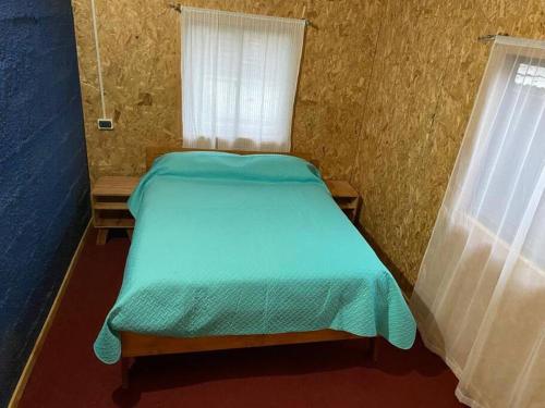 a small bedroom with a green bed with a window at Linda Casa en Carretera Austral in La Junta
