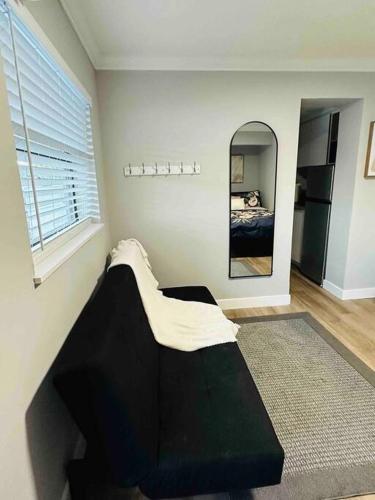 a bedroom with a black couch and a mirror at Coral Gables Miami Studio near Airport and Beaches in Miami