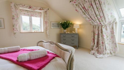 a bedroom with a bed with pink sheets and a window at Ty Gan y Mor in Nefyn