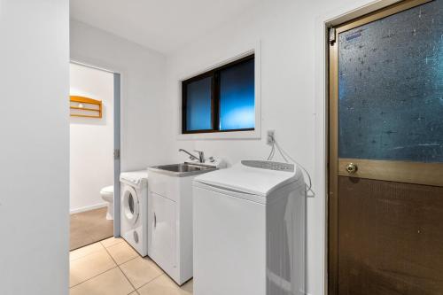 a bathroom with a washing machine and a sink at River Retreat, spa, pets, Wi-Fi in Turangi