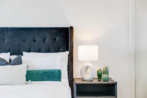 a bed with a black headboard and a table with a lamp at River Place hosted by AAB in Brisbane