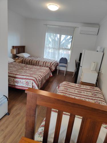 a room with two beds and a bench in it at Colonial Lodge Motel in Belmont