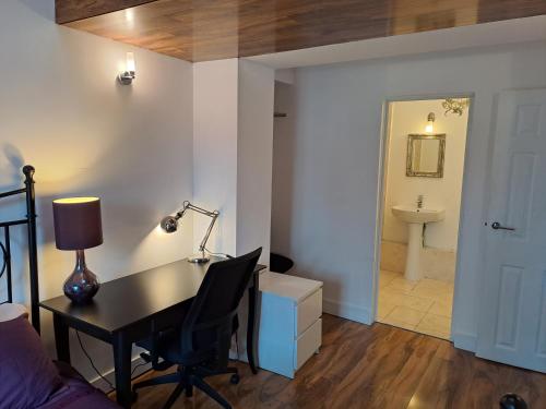 a bedroom with a desk with a lamp and a bathroom at Egham House Serviced Accommodation 5 Bedrooms 3 Bathrooms entire home, WiFi 1 Gbps, work desks, office chairs, TV 55" Roku, free parking, ONLY Company Stays welcome NO Leisure Stays, sleeps 6 in own beds in Staines