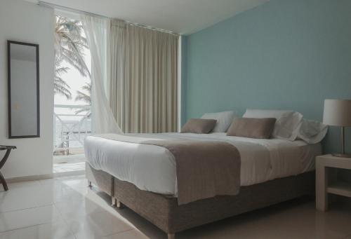 sypialnia z dużym łóżkiem i dużym oknem w obiekcie Hotel San Luis Beach House w mieście San Andrés