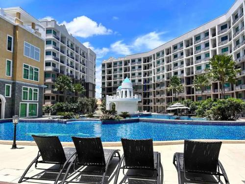 a pool with chairs in front of a large building at Lovely Pool View Arcadia 1 bedroom condo in Pattaya South