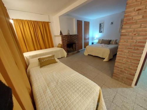 een woonkamer met 2 bedden en een open haard bij MAILY Guest House in Alta Gracia