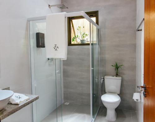 a bathroom with a toilet and a glass shower at Zaya Beach House em Ilhabela in Ilhabela