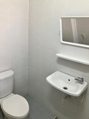 La salle de bains blanche est pourvue de toilettes et d'un lavabo. dans l'établissement Sataya Apartment, à Maha Sarakham