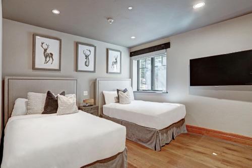 a bedroom with two beds and a flat screen tv at The Arrabelle at Vail Square, a RockResort in Vail