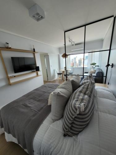 Un dormitorio con una cama grande y un televisor de pantalla plana. en Nuevo estudio al mar con cochera, en Mar del Plata