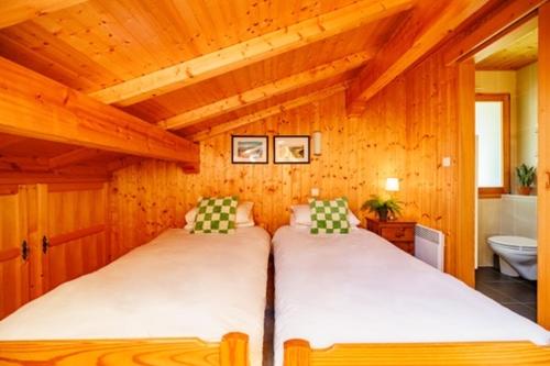1 dormitorio con 2 camas en una habitación de madera en Chalet Nicole, en La Côte dʼArbroz