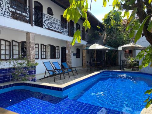 uma piscina em frente a uma casa com cadeiras e um guarda-sol em Magnu´s Pousada em Paraty