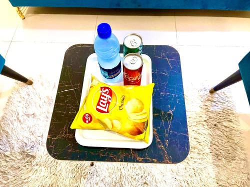 a tray with drinks and a bag of chips and a bottle of water at Go Room Hotel Lahore in Lahore