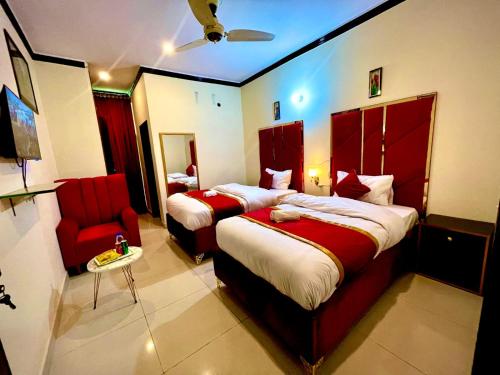 a hotel room with two beds and a red chair at Go Room Hotel Lahore in Lahore