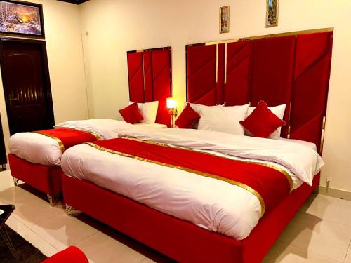 two beds with red headboards in a room at Go Room Hotel Lahore in Lahore