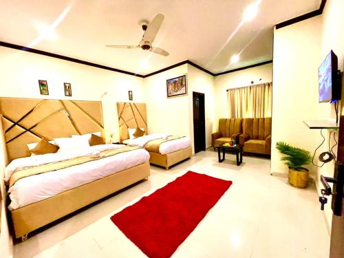 a bedroom with two beds and a red rug at Go Room Hotel Lahore in Lahore