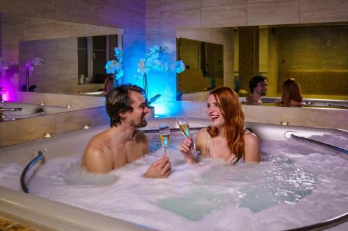 カルロヴィ・ヴァリにあるSpa Hotel MILLENIUM Karlovy Varyの浴槽に入った男女一杯のワイン