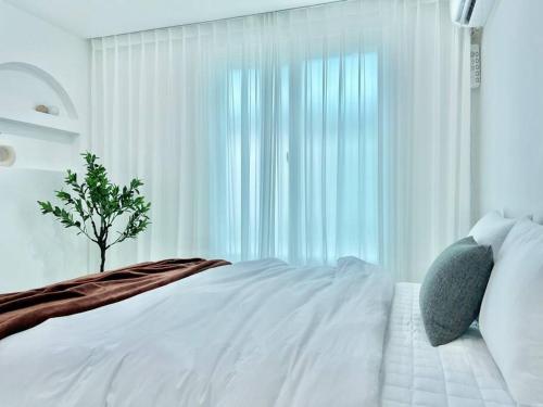 a bedroom with a white bed with a tree in front of a window at 3room+2bathroom hongdae 1exit in Seoul
