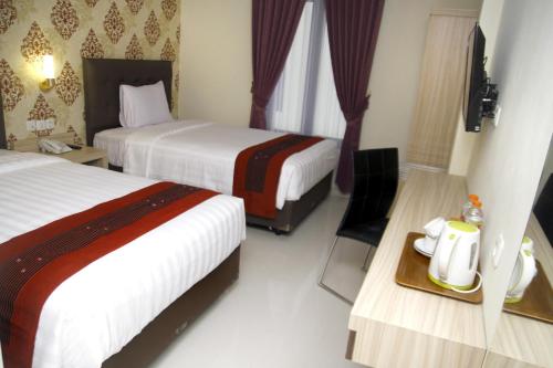 a hotel room with two beds and a table with a tray at Hersya Front One Inn Surabaya in Surabaya