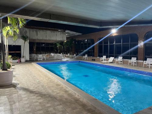 a large swimming pool with chairs and a building at Apartamento com vista da praia da Costa 615 in Vila Velha