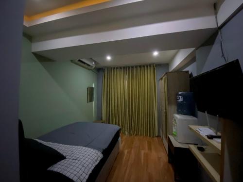 1 dormitorio con 1 cama y TV en Jarrdin Apartment by RumahKu, en Bandung