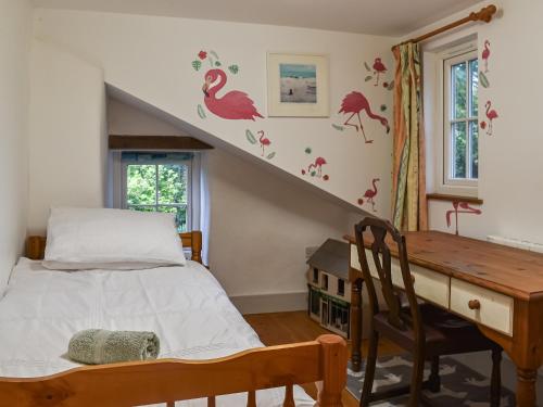a bedroom with a bed and a desk and a staircase at Bridge Cottage in Porkellis