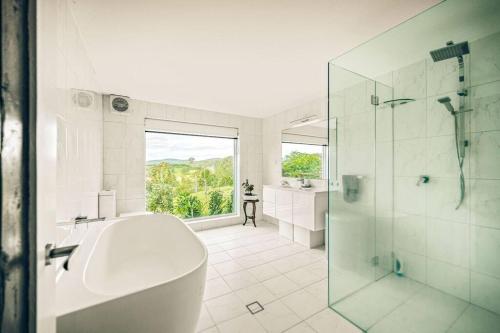 a white bathroom with a tub and a glass shower at The Tree House Bellingen in Thora