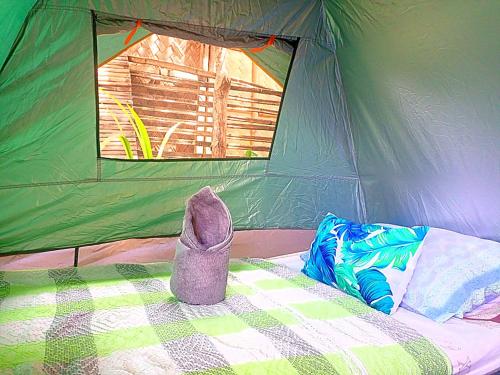 Tienda verde con un zapato en la cama en BH Beachfront Mini Glamping Tent, en El Nido