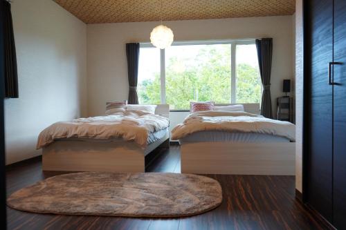 two beds in a room with a window at KIRAKU NAGI Niseko2BDRM Royal emerald garden 7 in Niseko