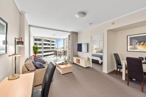 a living room with a couch and a dining room at Heart of the CBD ~ 1Bed/1Bath/Balcony/Free Parking in Brisbane