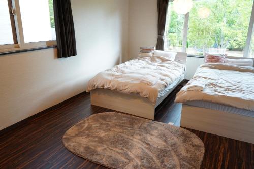 a bedroom with two beds and a rug and a window at KIRAKU NAGI Niseko2BDRM Royal emerald garden 7 in Niseko