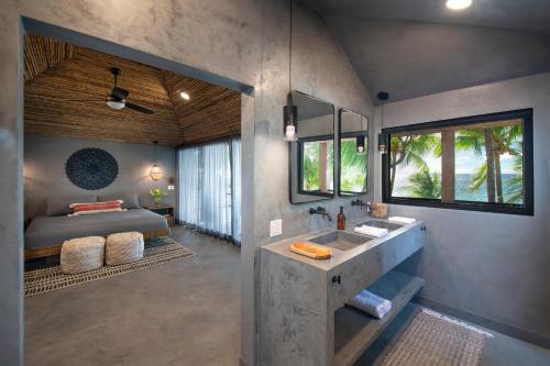ein Bad mit einem Waschbecken und ein Bett in einem Zimmer in der Unterkunft Arca in Roatán