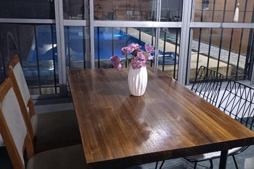 a vase of flowers sitting on top of a wooden table at Casa Olivia- Alojamiento con piscina - Aeropuerto Ezeiza in Ezeiza