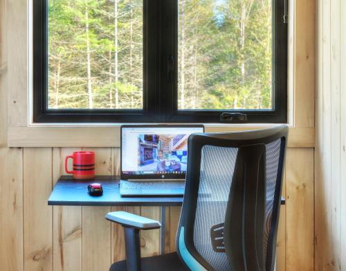 a desk with a laptop and a chair next to a window at Tremblant chalet O-Spa in Lac-Superieur