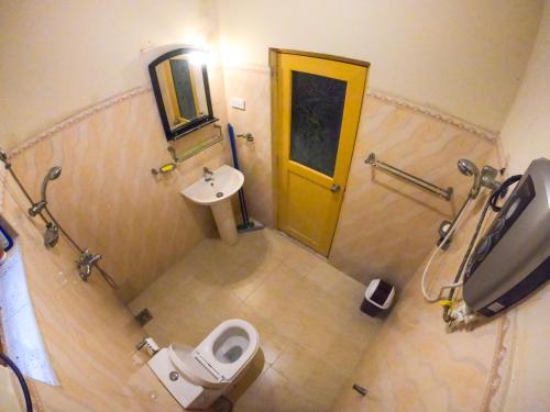 a bathroom with a toilet and a sink and a yellow door at Villa Girilena in Hikkaduwa