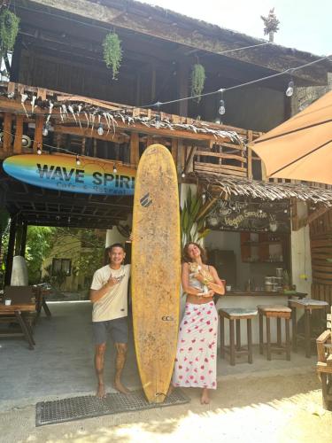 a man and a woman standing next to a surfboard at Wave Heaven 9 meters to cloud 9 in General Luna