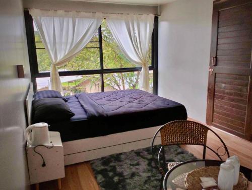 een slaapkamer met een bed en een groot raam bij Father's Garden Inthanon in Ban Na Yang