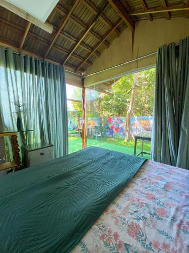 a bedroom with a bed and a large window at Suítes Naldiane in Imbassai