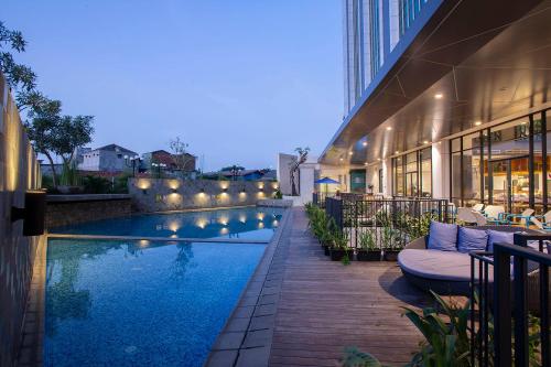 a hotel with a swimming pool next to a building at THE 1O1 Jakarta Airport CBC in Tangerang